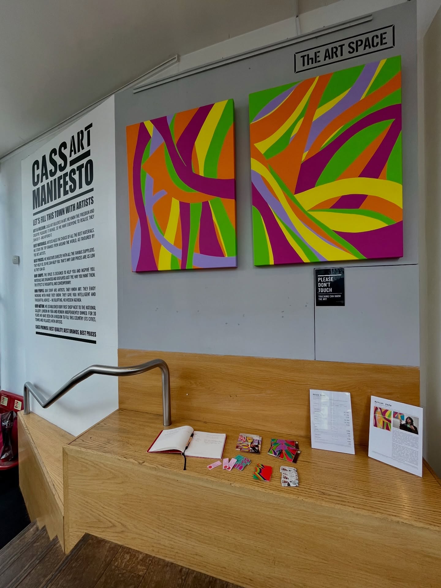 Two colourful Kika Pierides paintings installed in The Art Space at Cass Art