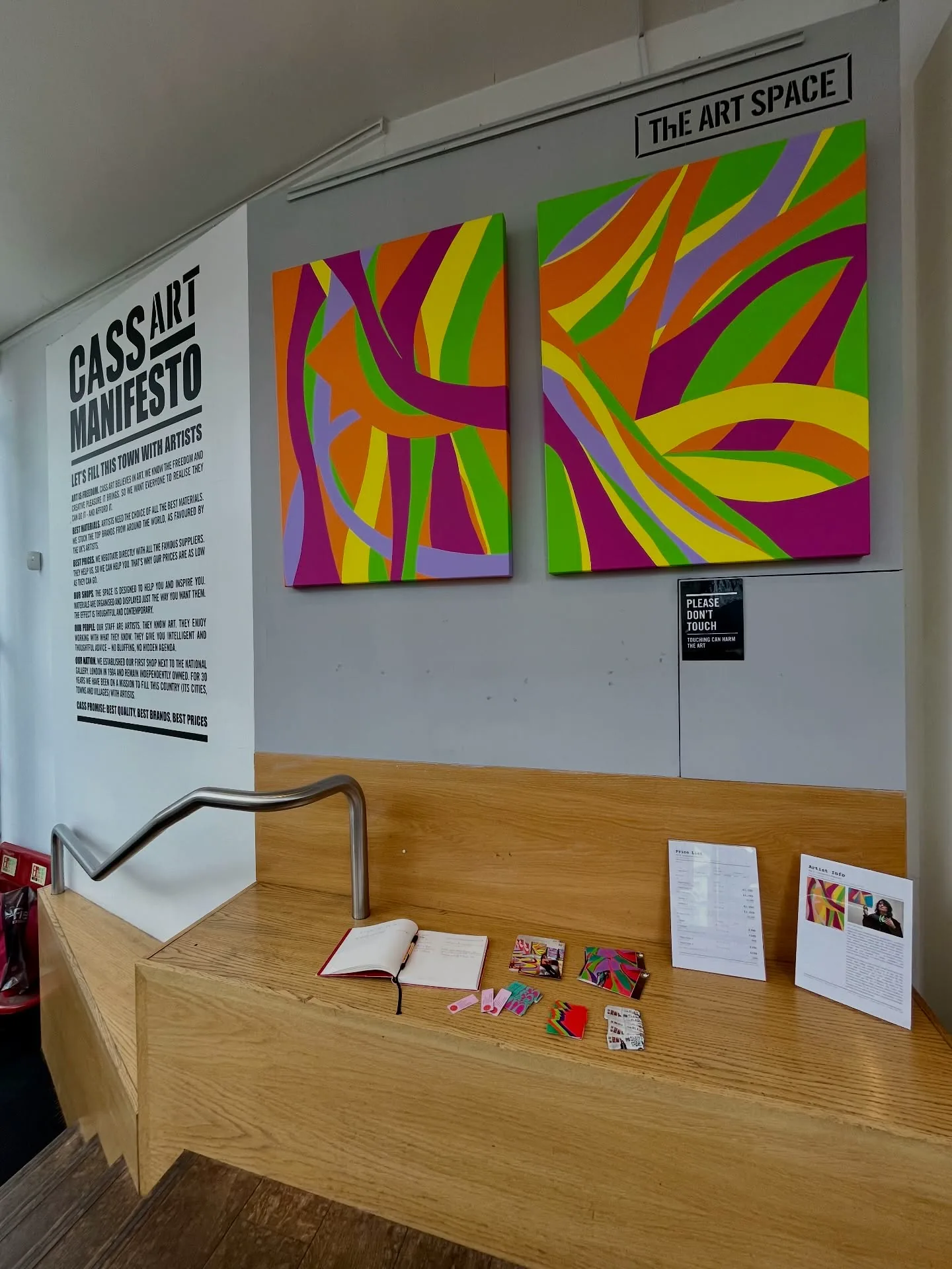 Two colourful Kika Pierides paintings installed in The Art Space at Cass Art