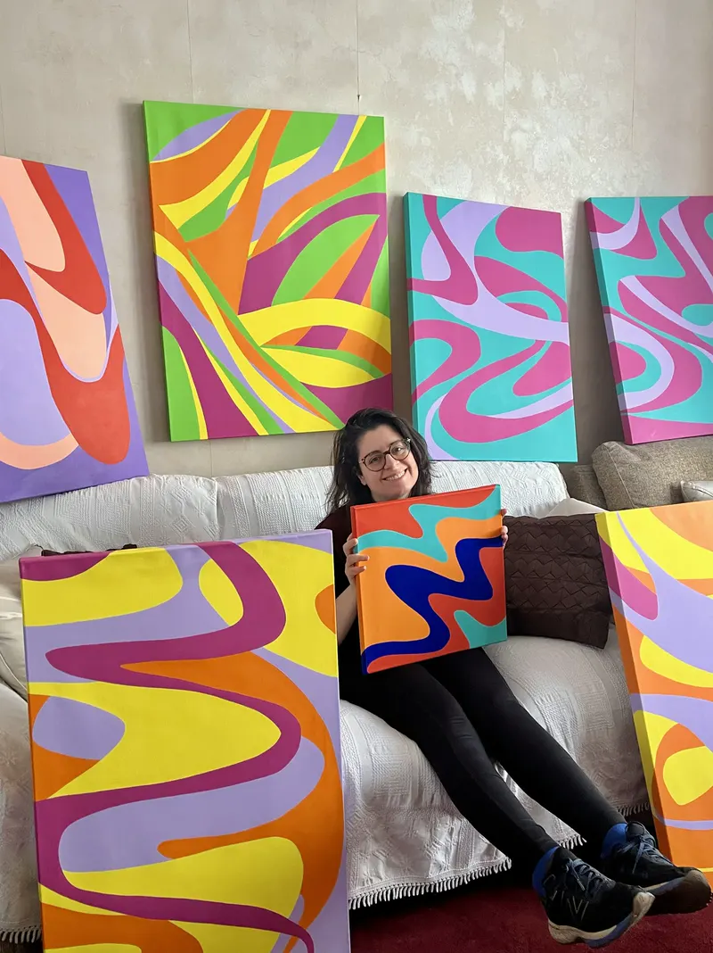 Contemporary patternist and textile artist Kika Pierides holding a colourful abstract painting