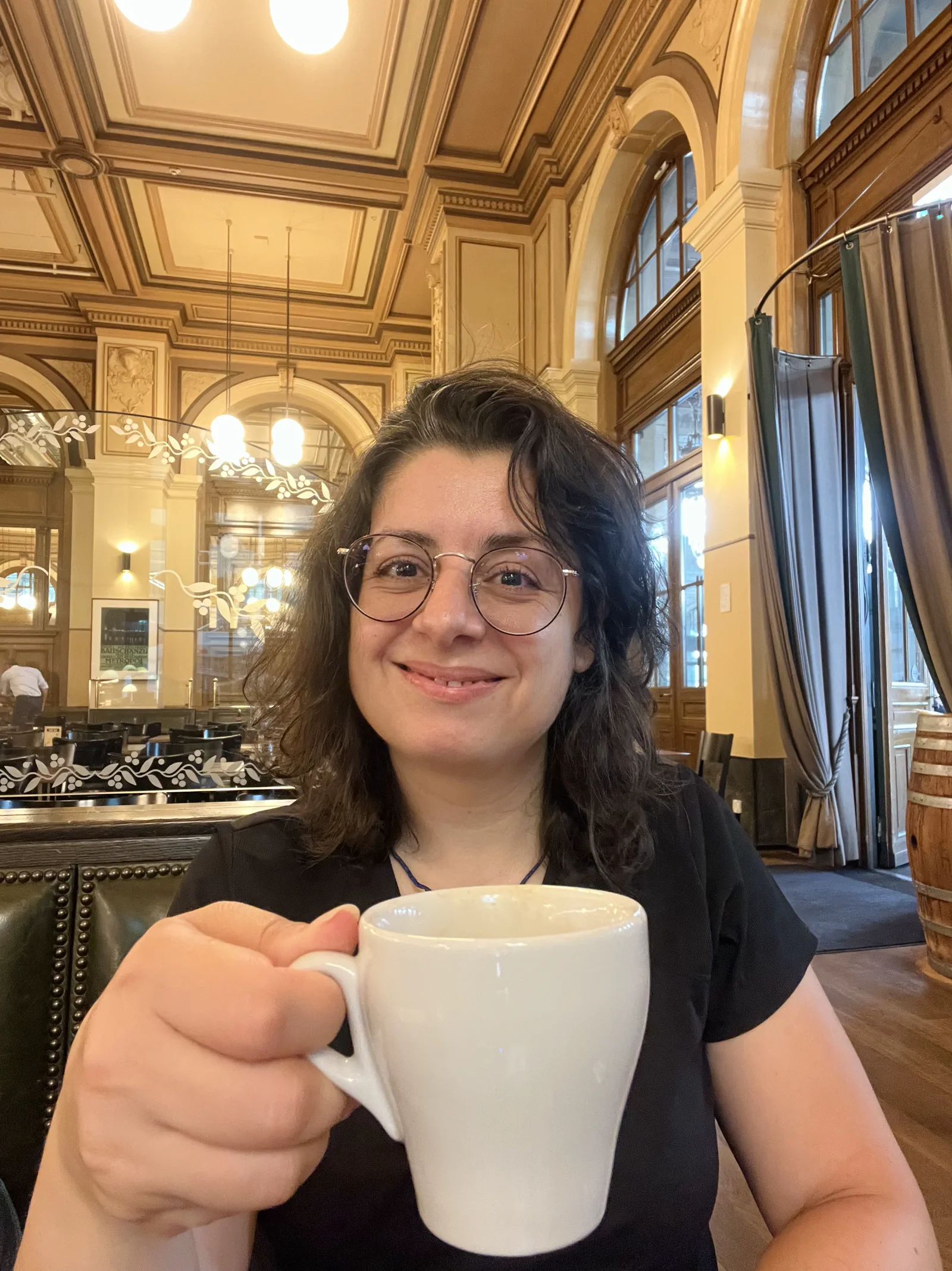 Kika Pierides smiling with a coffee in an ornate café, the cover image for Thoughts On Walks: Cyprus this September.