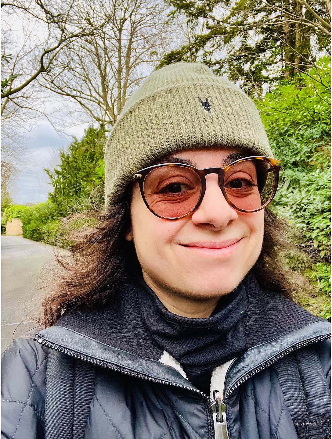 Woman beanie glasses selfie.