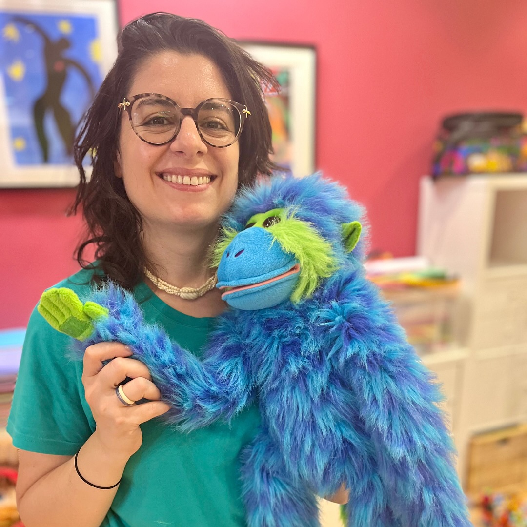 Woman holding blue puppet.