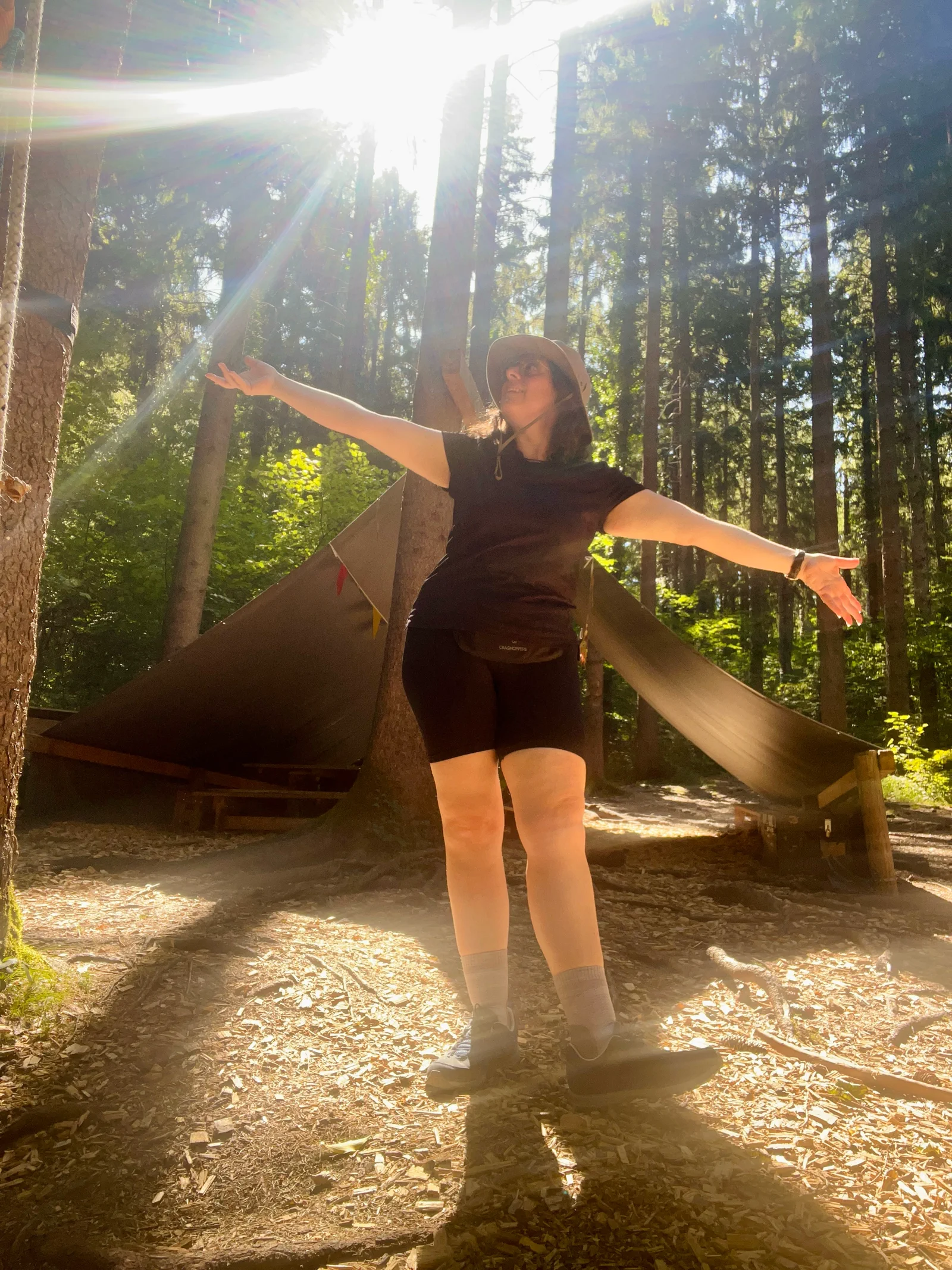 Kika Pierides standing in a sunlit forest during her Liechtenstein hike.