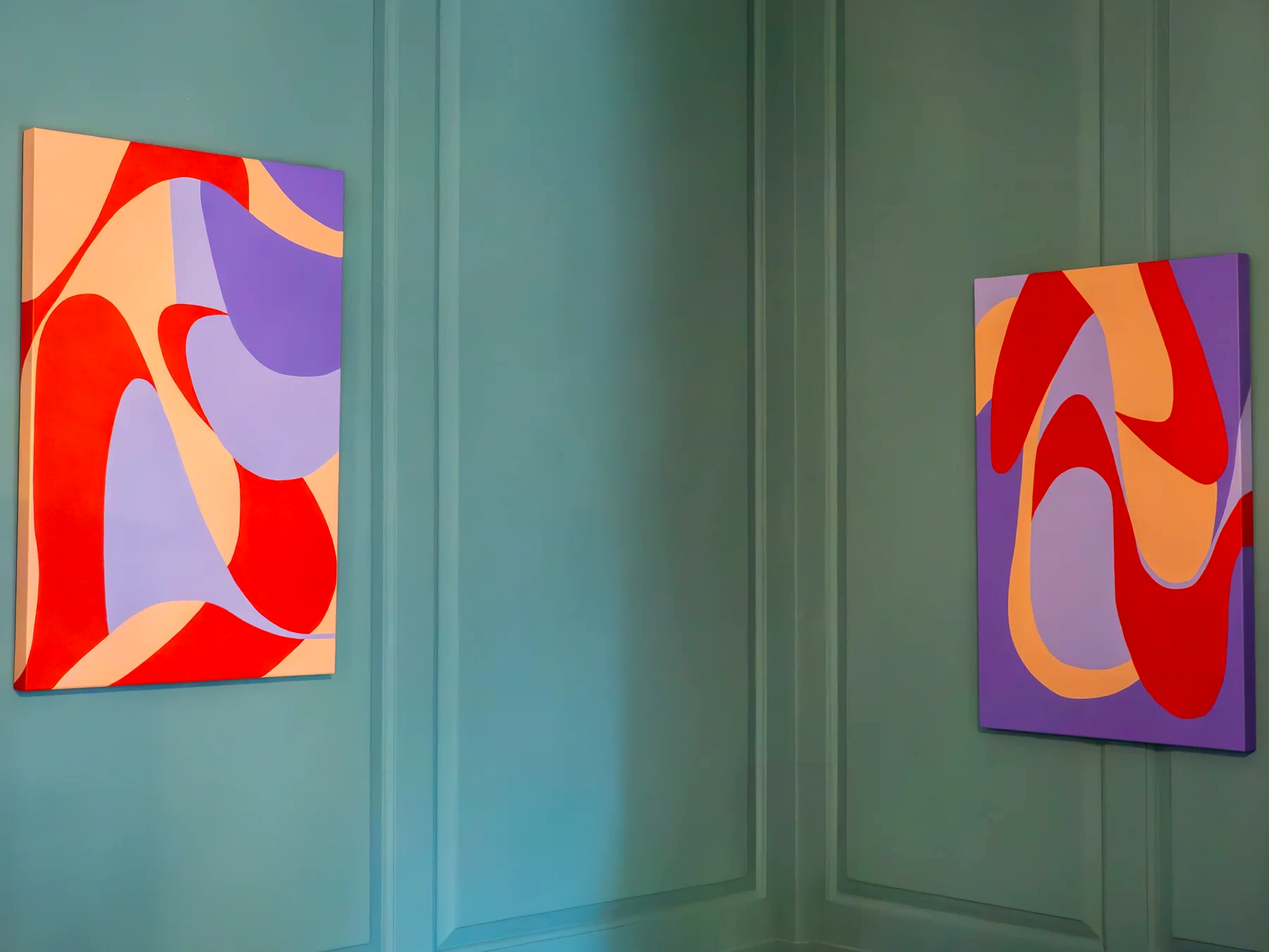 Two colourful paintings displayed across a blue-grey panelled room