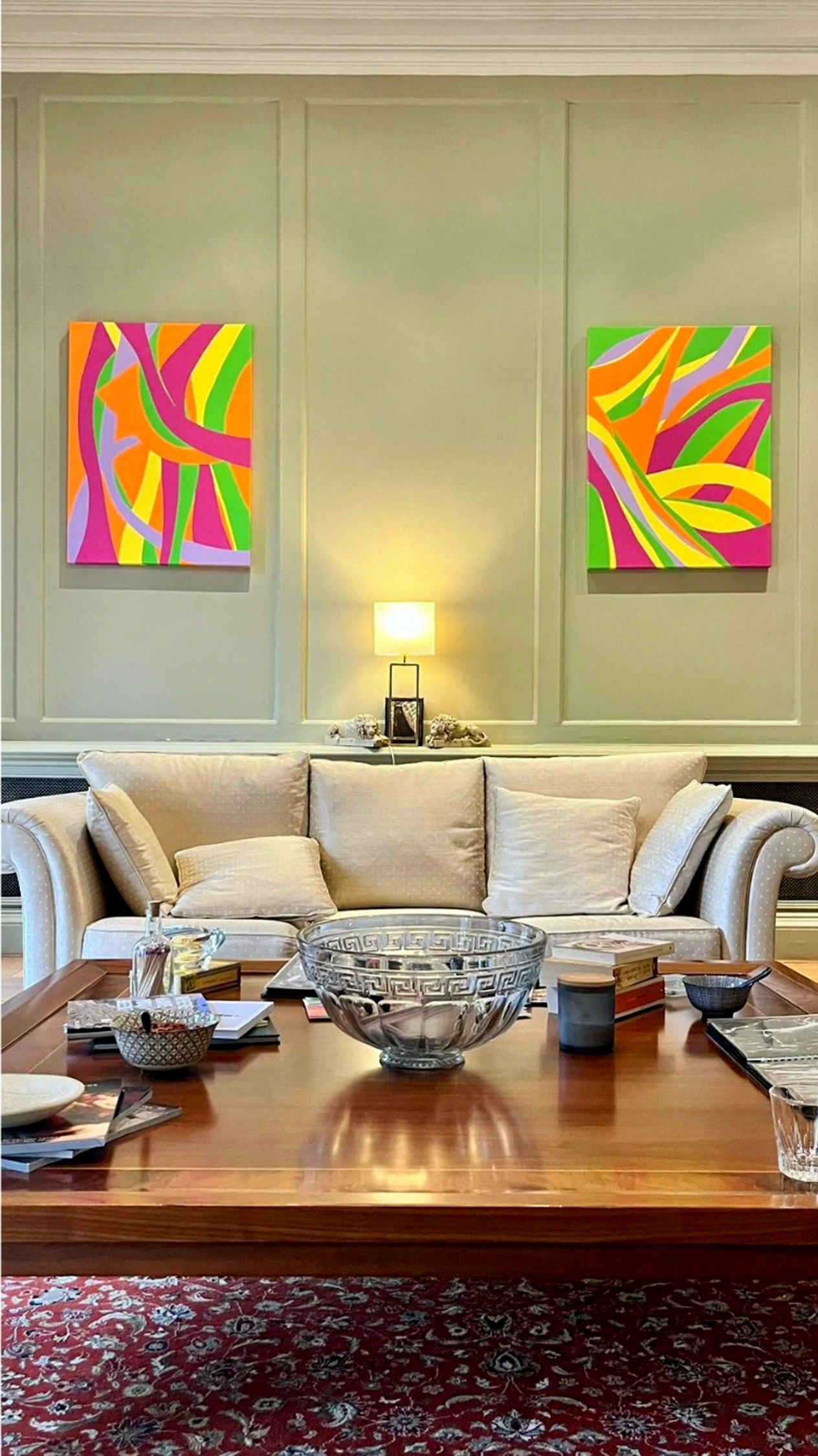A pair of colourful paintings displayed above a sofa in a formal living room
